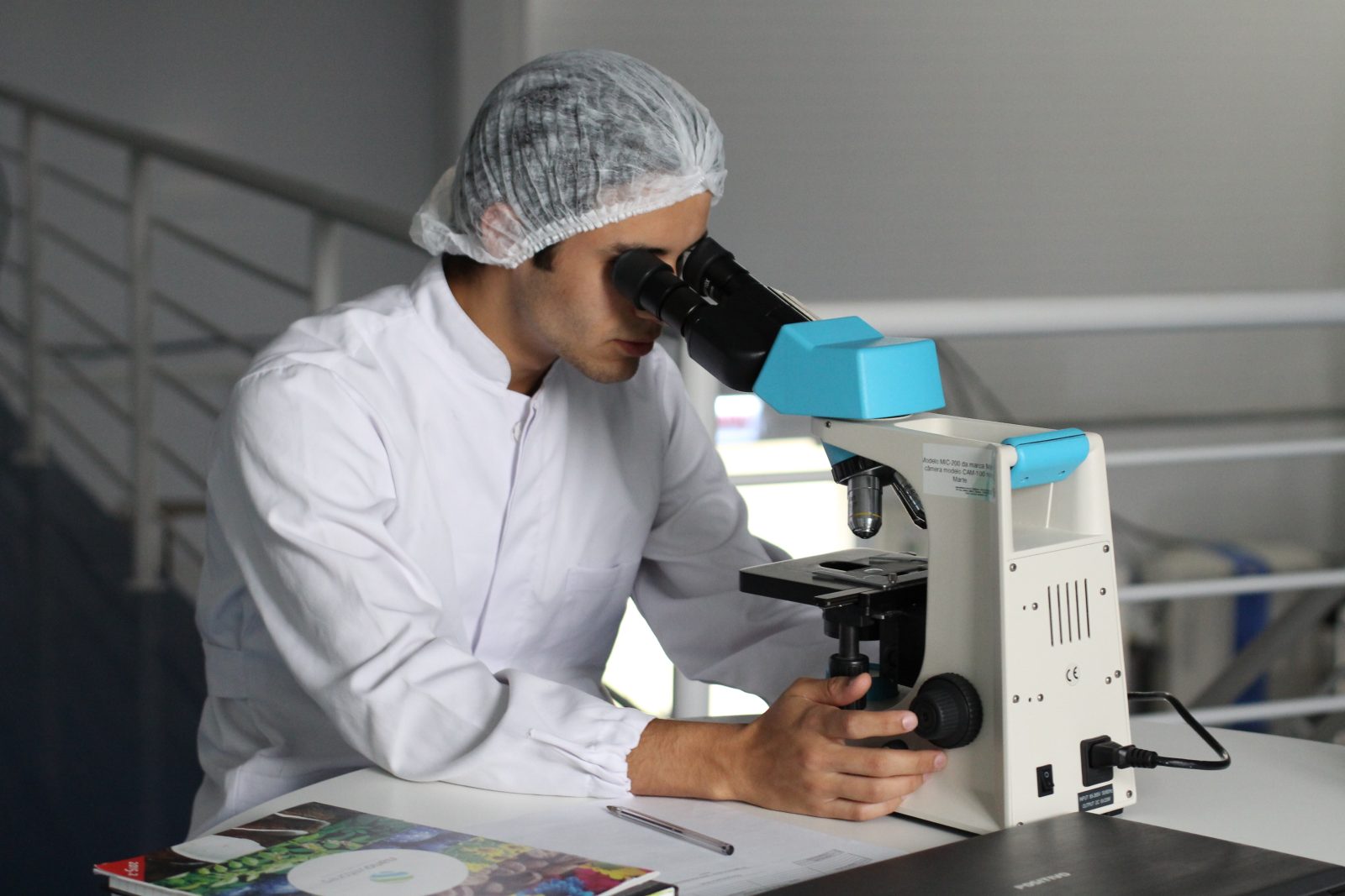 man in lab looking through microscope